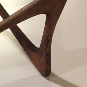 May include: Close-up of a dark cherry wood table leg with a triangular shape. The wood grain is visible and the finish is smooth.