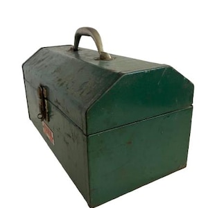 May include: A vintage green metal toolbox with a metal handle and a latch. The toolbox has a slightly rounded top and a rectangular base.