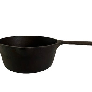 May include: A black cast iron saucepan with a single handle. The saucepan is empty and has a smooth, slightly rounded bottom.