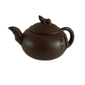 May include: A brown ceramic teapot with a lid and a handle. The teapot has a small, sculpted animal on the lid.