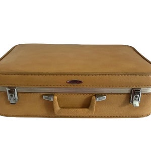 May include: A vintage tan leather suitcase with silver hardware and a white zipper.
