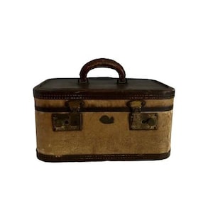 May include: A vintage brown leather suitcase with brass hardware and a top handle. The suitcase is made of a light brown material and has a worn look.
