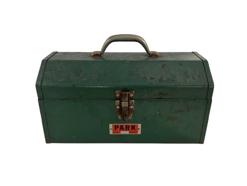 May include: Green metal toolbox with a silver handle and a latch. The toolbox has a label that says "PARK" in red letters.