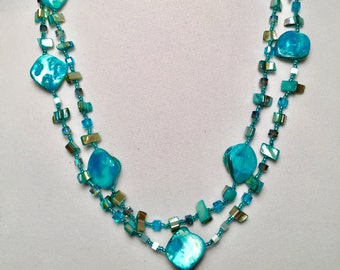 Peut inclure: Un collier turquoise à double rang avec des perles de coquillage irisées et des perles de verre transparentes.