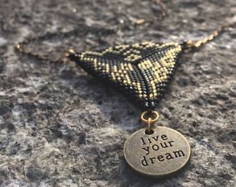 Peut inclure: Un collier en or avec un pendentif triangulaire noir et or et un charme rond qui dit "live your dream".
