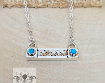 May include: Silver necklace with a rectangular pendant. The pendant features braided horse hair and two turquoise-coloured stones. The necklace has a delicate chain. The logo "Horse Hair Creations" is visible. The necklace is displayed on a wooden surface.