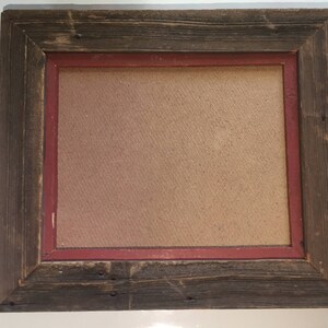 May include: A rustic wooden picture frame with a red inner border. The frame is made of reclaimed wood and has a natural, weathered finish.
