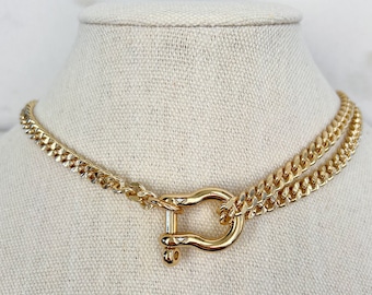 May include: A gold chain necklace with a large gold clasp. The necklace is layered and has a chunky chain design.