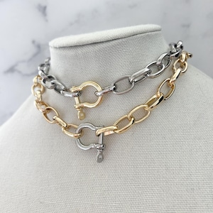Puede incluir: Dos collares de cadena exhibidos en un maniqu&iacute;. Uno es dorado, el otro plateado. Ambos presentan eslabones ovalados grandes y un cierre de grillete. Probablemente sean bisuter&iacute;a.