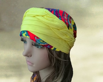 May include: A yellow turban with a colorful paisley print lining. The turban is folded and tied to create a unique style.