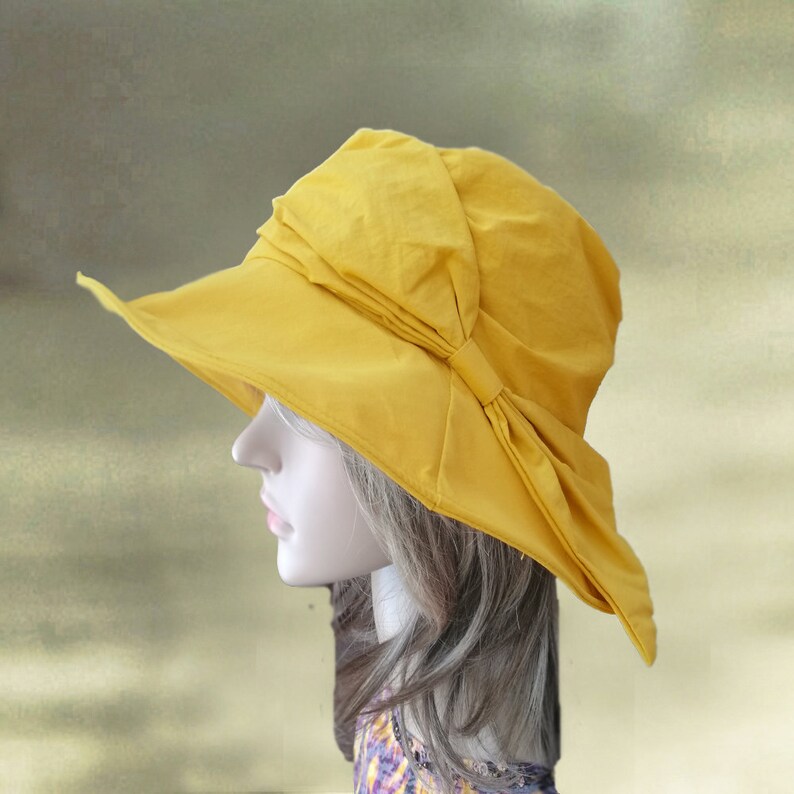 Puede incluir: Un sombrero de sol amarillo con un ala ancha y un lazo en un lado.