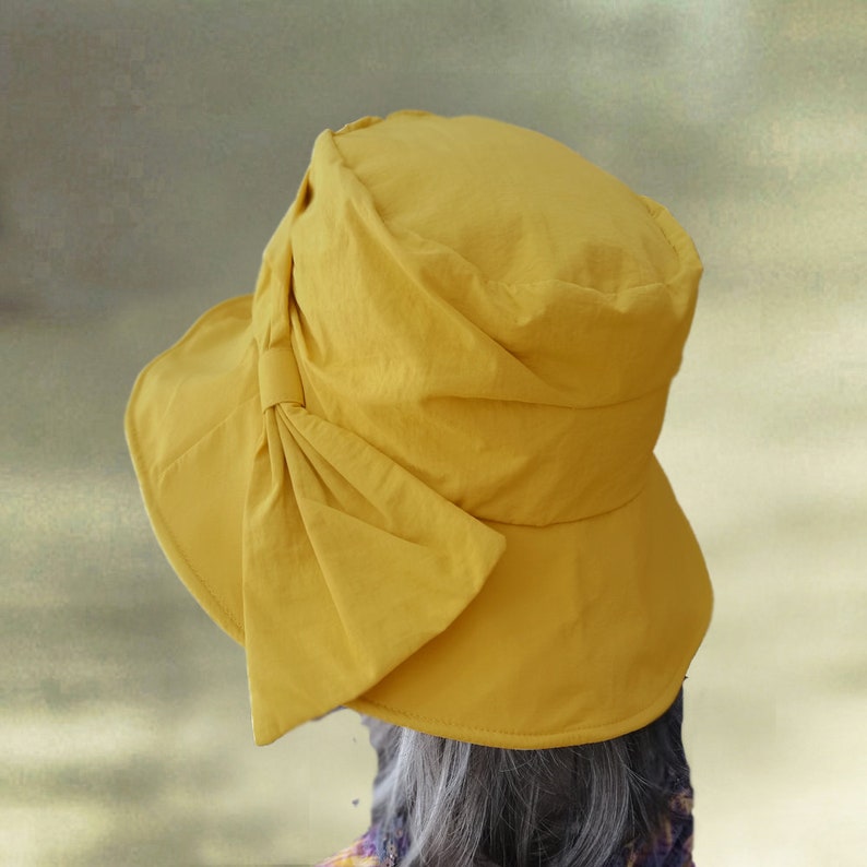 Puede incluir: Un sombrero de sol amarillo con un gran lazo en un lado. El sombrero est&aacute; hecho de una tela suave y ligera.