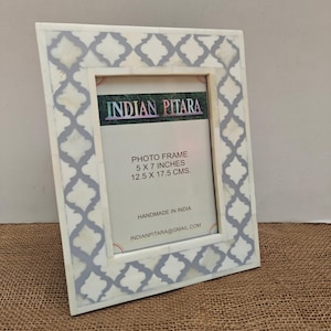 May include: A rectangular photo frame featuring a white and grey quatrefoil pattern. The insert displays the text INDIAN PITARA, PHOTO FRAME 5 X 7 INCHES 12.5 X 17.5 CMS., HANDMADE IN INDIA, and the email address INDIANPITARA@GMAIL.COM in black lettering.