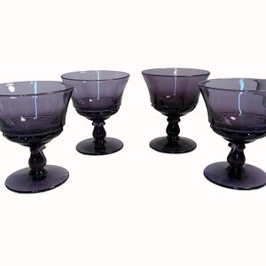 A group of four purple glass dessert cups arranged in a straight line against a white background.