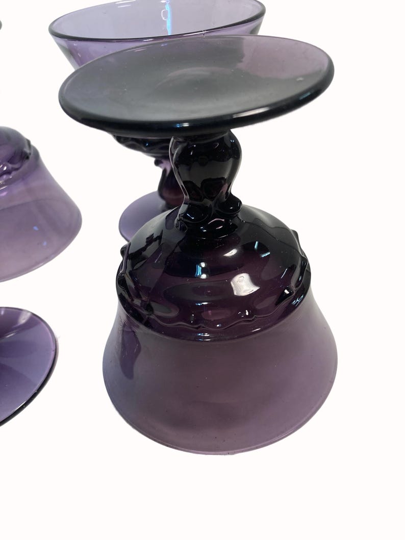 a close-up view of a set of purple glassware, including wine glasses and a bowl.