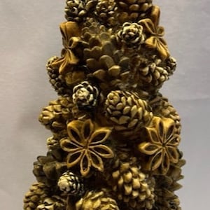 May include: A brown and white Christmas tree decoration made of pine cones and star anise. The tree is decorated with bows and is a festive addition to any holiday decor.
