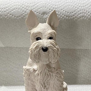 May include: White ceramic figurine of a sitting schnauzer dog. The dog has black eyes and a black nose.