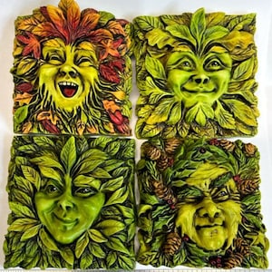 May include: Set of four green and brown ceramic wall plaques featuring whimsical faces surrounded by leaves. Each plaque depicts a different expression.