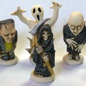 Op de afbeelding: Set van zes Halloween-figuurtjes, elk met een ander monster. De figuurtjes zijn gemaakt van keramiek en zijn geschilderd in felle kleuren. De set bevat een heks, een Frankenstein-monster, een spook, een doodgraver, een vampier en een pompoenkop-vogelverschrikker.