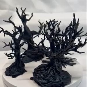 May include: Three black, 3D printed, miniature, gnarled, dead trees with twisted branches. The trees are set on a white surface.