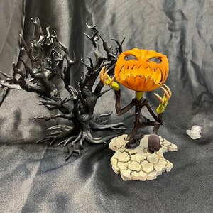 May include: A Halloween-themed figurine of a pumpkin-headed figure with a skeletal body and long, sharp claws. The figure is standing on a rocky base and is posed in a menacing stance. The figure is surrounded by a black, twig-like tree.