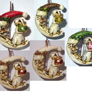 May include: Set of four Christmas ornaments featuring a white mouse holding a red, green, or gold ornament, perched on a crescent moon with a Santa-like figure. Each ornament has a different color scheme.