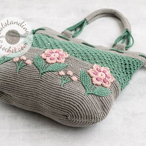 Crochet bag pattern: a shoulder bag with a combination of embossed crochet bottom with 3D flowers and leaves and a net top. Beautiful original multi-corded handles and a drawstring that goes through the top.