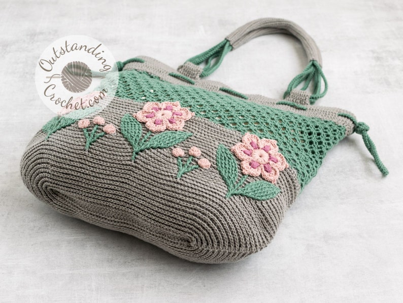 Crochet bag pattern: a shoulder bag with a combination of embossed crochet bottom with 3D flowers and leaves and a net top. Beautiful original multi-corded handles and a drawstring that goes through the top.