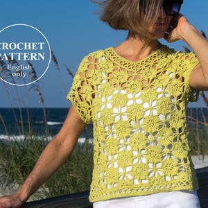 Puede incluir: Un top de ganchillo amarillo claro con un patrón floral. El top tiene mangas cortas y cuello redondo. El texto "CROCHET PATTERN English only" está en un círculo blanco en la esquina superior izquierda. El fondo muestra una playa y el océano.