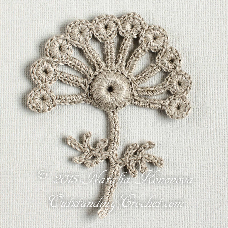 May include: A crocheted flower motif in beige with a stem and leaves. The flower has a central circle with a smaller circle in the centre. The flower is surrounded by a ring of smaller circles.