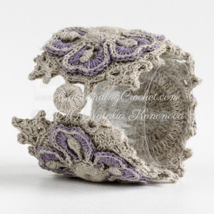 May include: A crocheted bracelet with a floral design in shades of beige and purple. The bracelet is made with a delicate stitch and features a raised flower pattern. The text "www.OutstandingCrochet.com &copy;2016 Natalia Hononova" is visible on the bracelet.
