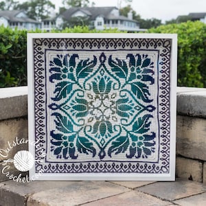 Peut inclure: Une pièce de crochet encadrée avec un fond blanc et un motif répétitif de feuilles et de fleurs vertes et bleues.