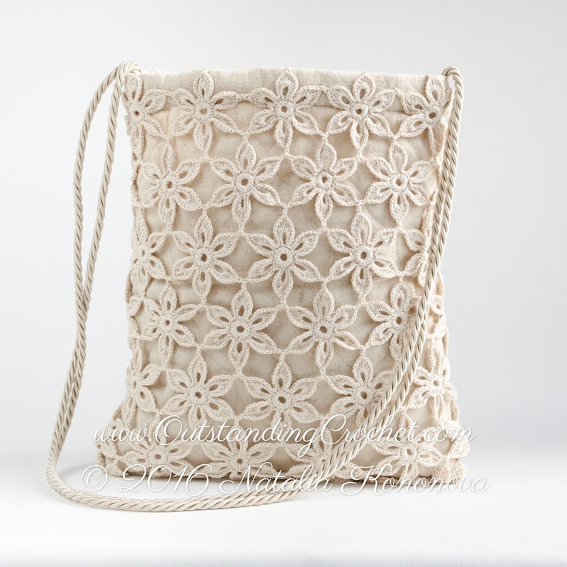 May include: A crocheted bag with a floral design and a beige rope strap. The bag is made of a light beige fabric and has a drawstring closure. The text "www.OutstandingCrochet.com &copy; 2016 Natalia Rohonkova" is visible on the bag.