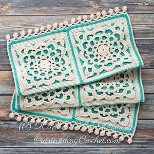 Puede incluir: Una pila de cuatro cuadrados tejidos a crochet con un borde turquesa y detalles de crochet blanco. Los cuadrados tienen un borde de flecos con pompones blancos. Los cuadrados est&aacute;n sobre una superficie de madera. (C) 2018 Natalia Honcharova OutstandingCrochet.com