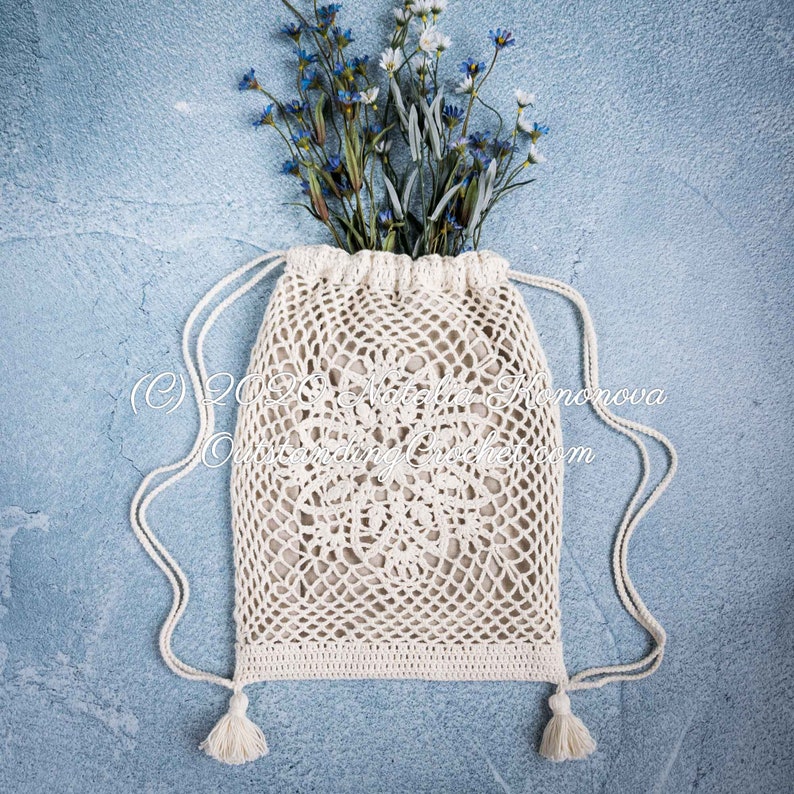 Crochet bag pattern: Lotus lace drawstring backpack with beautiful lace motifs on moth sides and fabric lining, decorated with tassels.