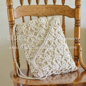 May include: A crocheted bag with a floral design, featuring a beige color and a rope strap. The bag is sitting on a wooden chair.