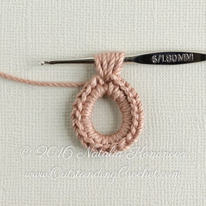 May include: A close-up of a crocheted ring made with a light pink yarn. The ring is being worked on with a 6/1.80 mm crochet hook.