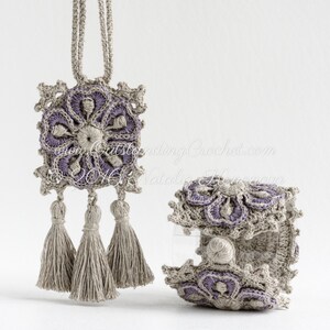 May include: A set of crocheted jewelry featuring a pendant with a square design and three tassels, and a bracelet with a similar design. Both pieces are made with beige and purple yarn.