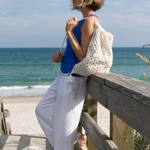 Crochet bag pattern: Lotus lace drawstring backpack with beautiful lace motifs on moth sides and fabric lining, decorated with tassels.