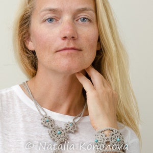 K&ouml;nnte beinhalten: Eine Frau tr&auml;gt ein wei&szlig;es Hemd mit einer geh&auml;kelten Halskette und einem Armband. Die Halskette hat einen Quasten und sowohl die Halskette als auch das Armband haben t&uuml;rkisfarbene Perlen. Der Text "&copy; Natalia Konova OutstandingCrochet.com" ist im Bild sichtbar.