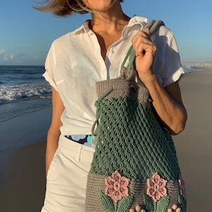 Crochet bag pattern: a shoulder bag with a combination of embossed crochet bottom with 3D flowers and leaves and a net top. Beautiful original multi-corded handles and a drawstring that goes through the top.