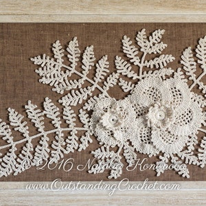 May include: A framed crocheted wall art piece featuring a white fern design with a crocheted flower in the center. The artwork is displayed on a brown burlap background.