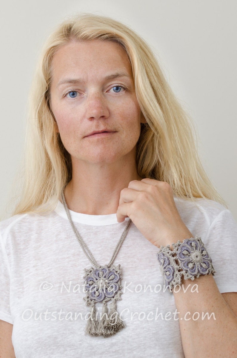May include: A woman wearing a white t-shirt with a crocheted necklace and bracelet. The necklace and bracelet are made of beige and purple yarn and feature a floral design. The text "&copy; Natalia Konovova Outstanding Crochet.com" is visible on the t-shirt.