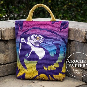 May include: A crocheted tote bag with a colorful parrot design. The bag has a yellow handle and is made with a gradient of pink, blue, purple, and yellow yarn. The bag has the text "CROCHET PATTERN" in a circle with the words "English" and "Dutch" below it.