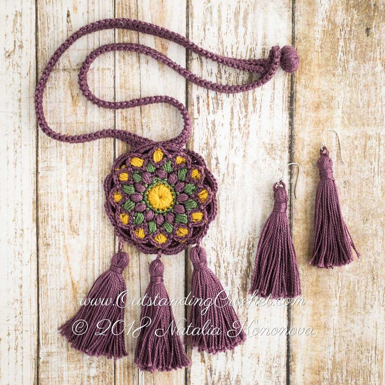 May include: A crocheted necklace with a purple cord and a round, multi-colored crocheted pendant with tassels. Matching purple tassel earrings are also included. The text "www.OutstandingCrochet.com &copy; 2018 Natalia  Konovova" is visible in the image.