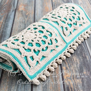 Puede incluir: Una alfombra de crochet con un dise&ntilde;o blanco y turquesa. La alfombra est&aacute; enrollada y tiene flecos en los bordes. La alfombra est&aacute; sobre una superficie de madera. (c) 2018 Natalia Konova OutstandingCrochet.com