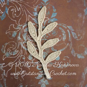 May include: A crocheted leaf design in a beige color. The leaf is made of yarn and has a delicate, intricate pattern. The leaf is on a brown background with a blue and white pattern.