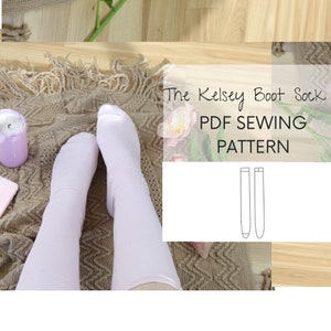 Può includere: Un paio di calze bianche al ginocchio su un tappeto marrone con il testo "The Kelsey Boot Sock PDF Sewing Pattern" e un disegno a linea del modello del calzino.