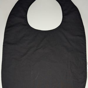 May include: A black cotton bib with a velcro closure. The bib is designed for babies and toddlers.