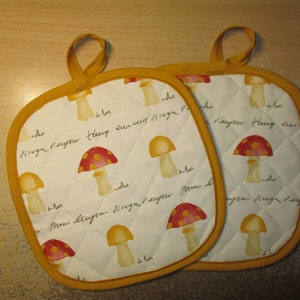 May include: Two yellow and white quilted pot holders with a mushroom pattern and the text "Mom, I love you" in cursive.